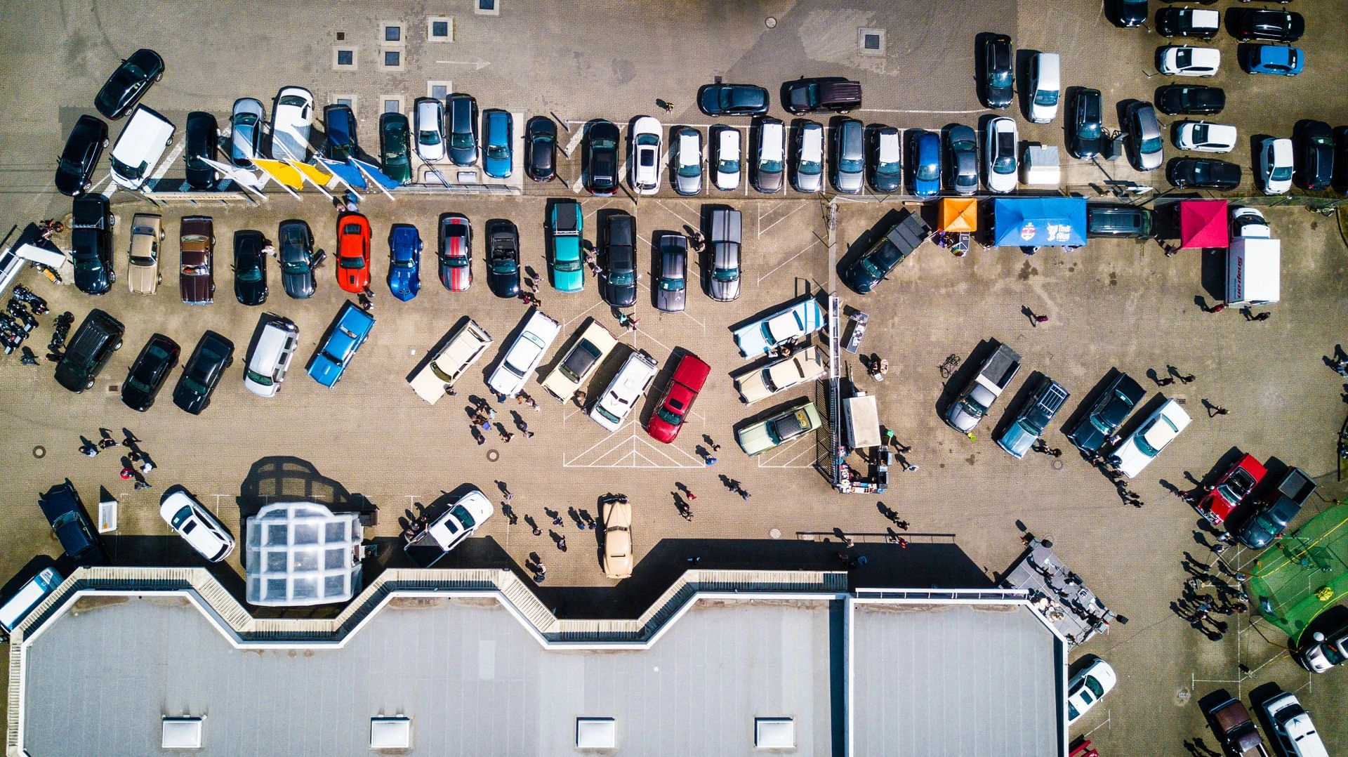 Aerial drone view of a wholesale auto auction lot with rows of vehicles lined up for sale day.
